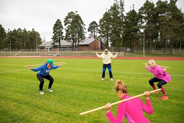 Lauritsalan urheilukeskuksen nurmikentällä kuntoilijoita keppijumppaamassa, katsomo ja uimahalli näkyy taustalla